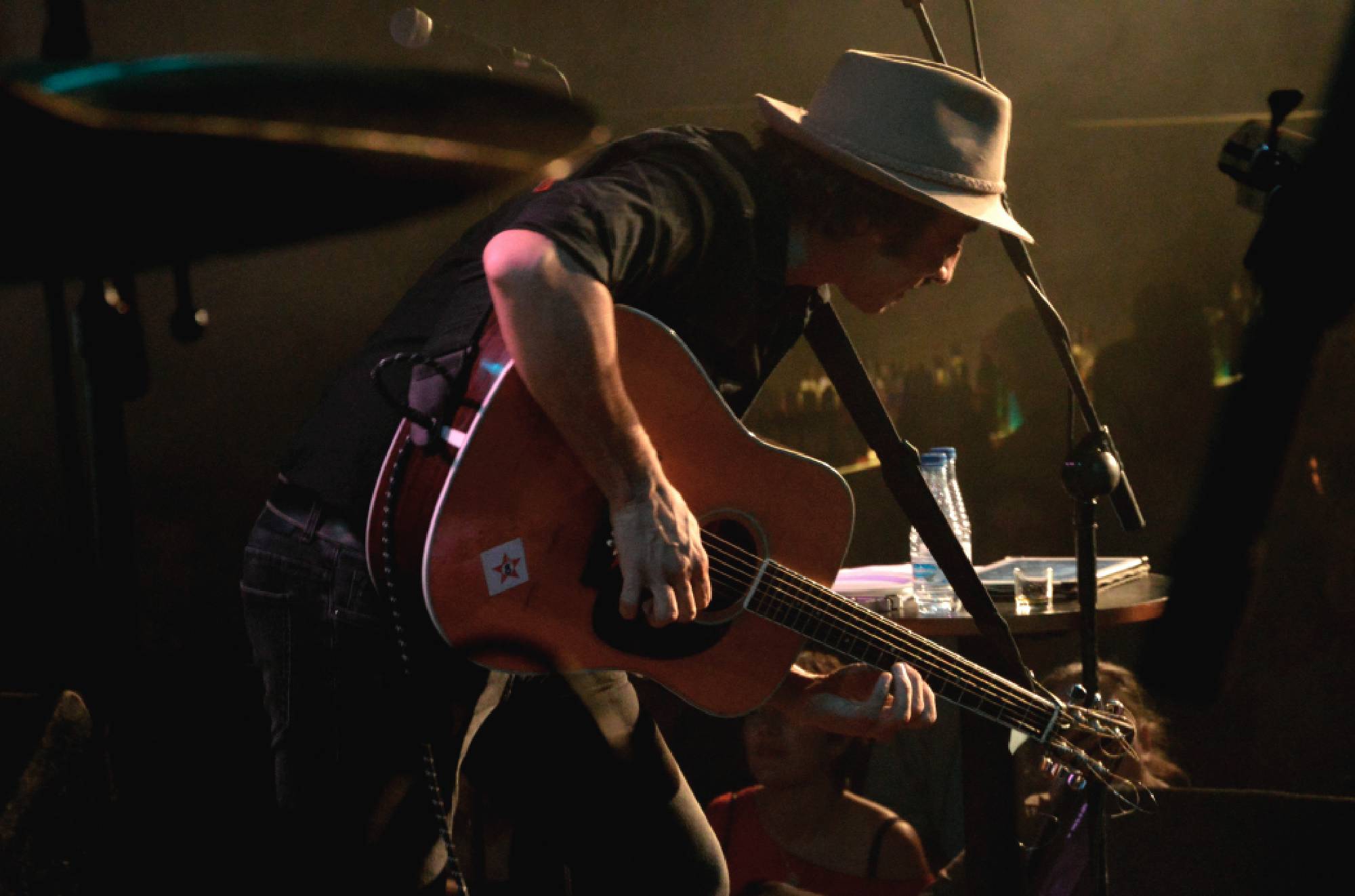 Lucas Masciano inclinado sobre su guitarra en un escenario de luz tenue
